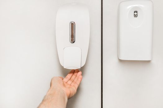 The man raised his hand to the soap dispenser next to the fresh air spray.