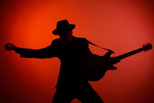 silhouette of a guitarist in a hat on a red background.