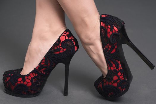 women's legs in red lace shoes with high black heels isolated on background