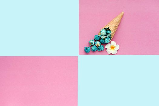 Popcorn spill out from waffle ice cream cone on pastel colorful background. Blue fruitful Popcorn on a cone cornucopia Top view bright hipster background.