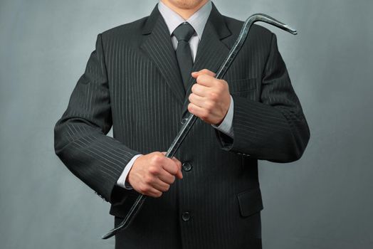 Unrecognizable businessman in a suit holds crowbar, businessman ready to take the business