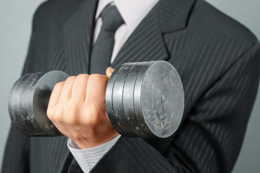 Unrecognizable businessman in a suit holds dumbbell