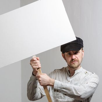 Working in a cap holding a banner over his head at white wall