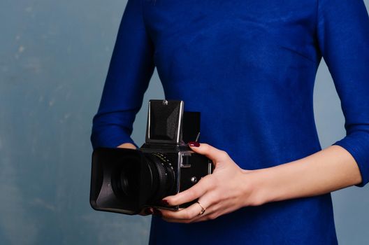Girl in vintage blue dress holding old medium format camera.