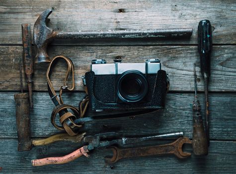 Set of old working tools and retro photo camera on wooden table, top view