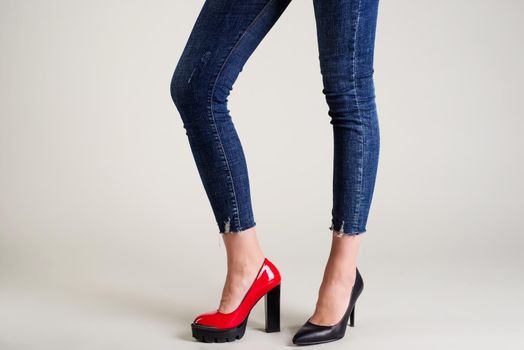 Woman legs in summer shoes isolated over neutral background. select your pair concept - red or black shoes