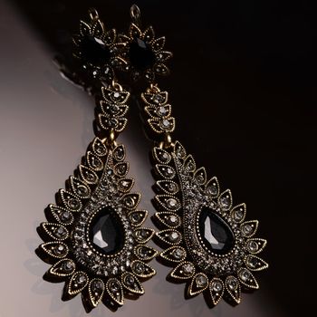 silver earrings with black stones on dark glass