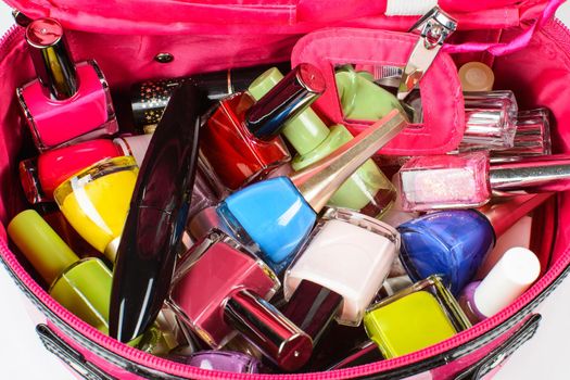 Set of nail polish, mascara, nail clippers, in a pink purse.