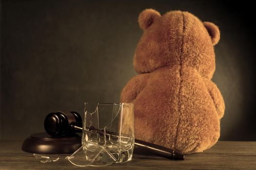 Teddy bear, judge's hammer, broken glass. The concept of deprivation of parental rights or divorce due to alcoholism. - image