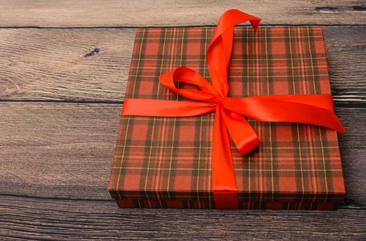 Small gift box with red ribbon on wooden table