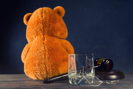 Teddy bear, judge's hammer, broken glass. The concept of deprivation of parental rights or divorce due to alcoholism. - image
