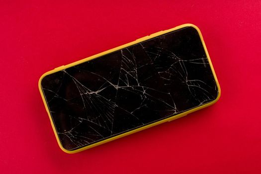 Smartphone with broken screen on red background - image