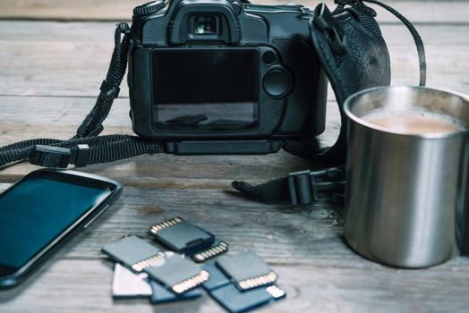 Digital photo camera, memory cards and mobile phone on wooden table