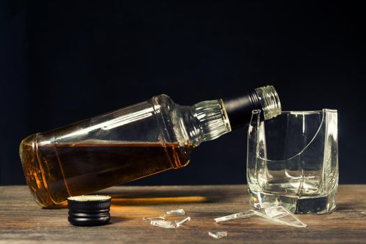 Broken glass and a bottle of whiskey. The concept of ruined life due to alcoholism. - image