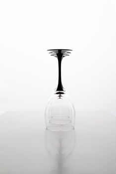 Closeup of three transparent clear crystal empty three inverted wine glasses grey background, vertical picture