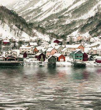 wooden houses on the banks of the Norwegian fjord, beautiful mountain landscape in winter