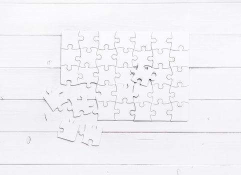 white unfinished puzzle isolated on white wooden table