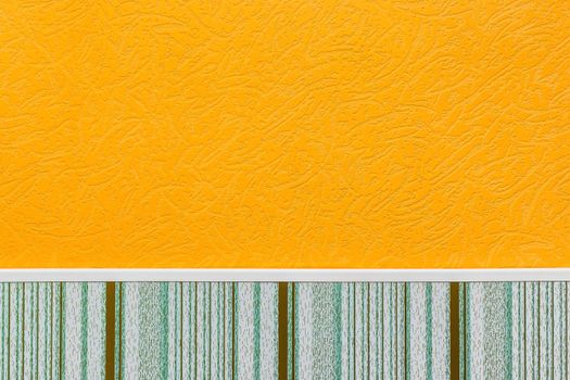 Element or part of wall of modern interior with orange wallpaper with abstract pattern and plinth with vertical lines texture background.