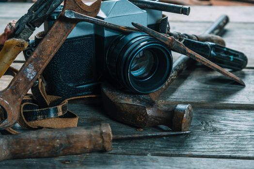 Old working tools and retro photo camera on wooden table. With a vintage retro filter. Dark picture tone.