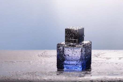 Perfume in blue bottle with water droplets