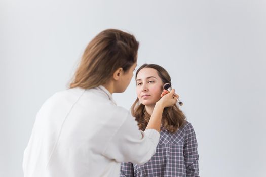 Beauty and cosmetics concept - Makeup artist doing professional make up of young woman.