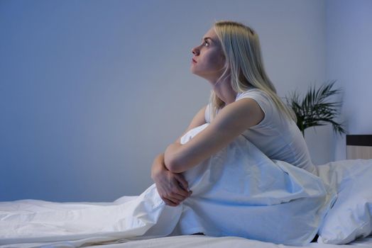 Sad depressed woman sitting in her bed late at night, she is pensive and suffering from insomnia - Image