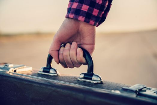 Close-up image of female hand with retro suitcase, face is not visible