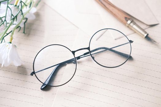 notepad, eyeglass and a pencil on wooden table .