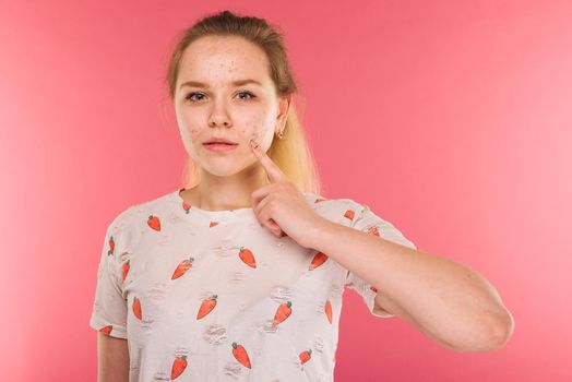 Portrait of teen girl touching her face and looking for acne on ruby background