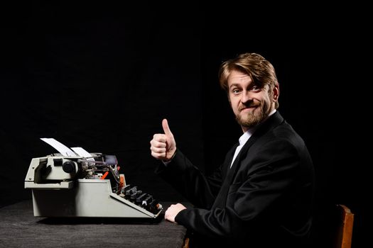 writer, a man in a black jacket typing on typewriter on a black background