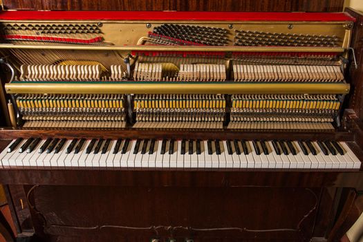 old broken piano standing at the wall
