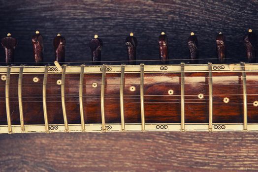 Close-up of a fingerboard Indian musical instrument sitar lying on a wooden floor - image Toned