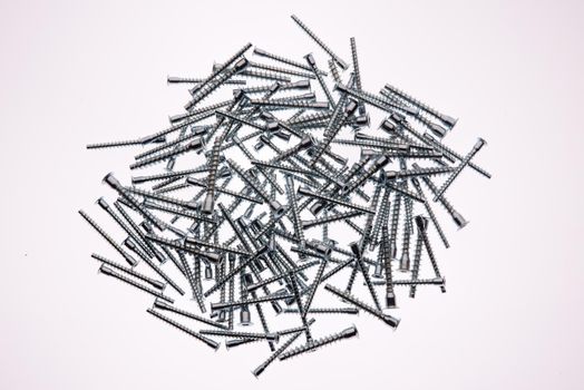 Mound of furniture screws top view on white background- image