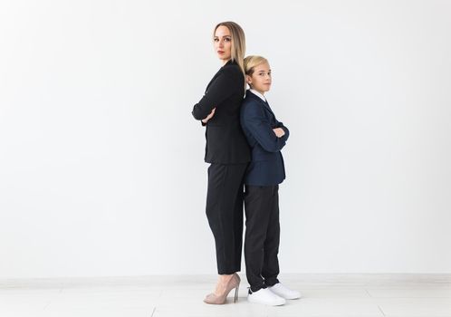 Teenager and single parent - Young mother and son standing together, back to back on white background with copyspace.