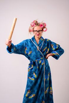 smiling woman housewife in a dressing gown and curlers with a ladle in her hand.