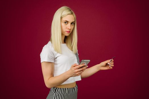 A young woman holds a smartphone and a credit card in her hands. Problems with a bank card, because of blocking or incorrectly entered pincode. Communication with customer support