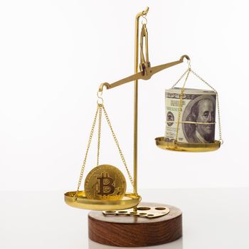 Bitcoin value increase trend. The coin outweighs the balance. On another bowl a stack of hundred dollar bills. White background - image