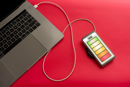 Mobile phone on red desk office charge with computer. - image
