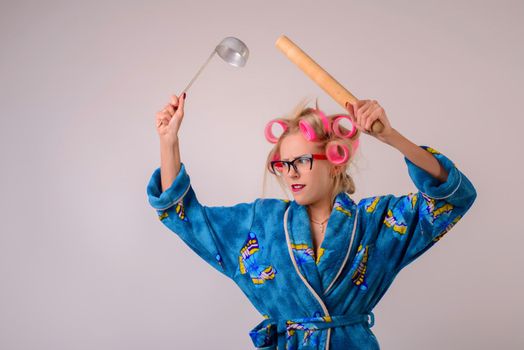 Screaming crazy housewife in a dressing gown and curlers with a ladle and battledore.
