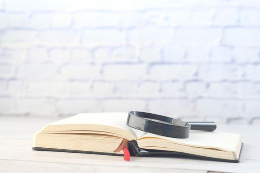 open book and magnifying glass on table