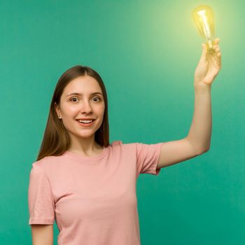 Cute girl student holds a lamp in her hand isolated on a background. The concept of an idea or creative insight.