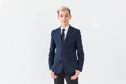 Portrait of stylish school boy teenager in white shirt and jacket against white background with copy space