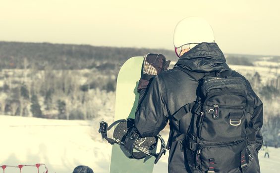 people in ski suit holding snowboards on a snowhill view from back