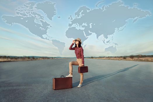 Traveler woman with suitcase looks on road. World map in the sky