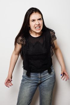 Close up of an attractive young woman with a horrified expression clenching her hands in frustration and desperation as she stares open-mouthed at the camera.