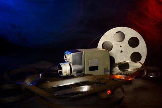 8 mm movie camera with a reel of film in blue and red smoke. dark background
