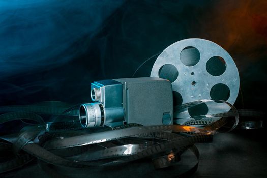 8 mm movie camera with a reel of film in smoke. dark background
