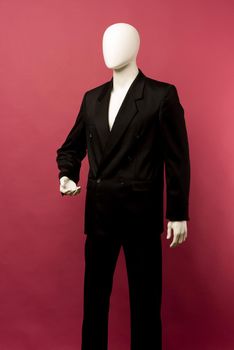 White male mannequin in a black business suit on a ruby background - image