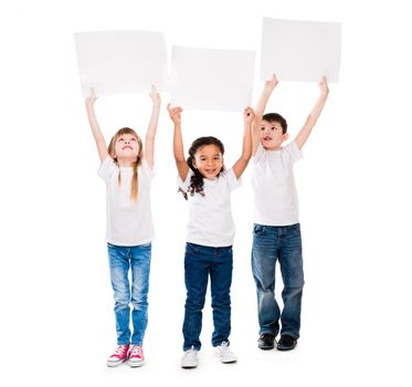 three cheeerful children holding en empty paper sheet above themselves isolated on white background