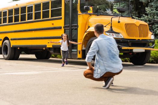 Father meeting little daughter coming out of school bus